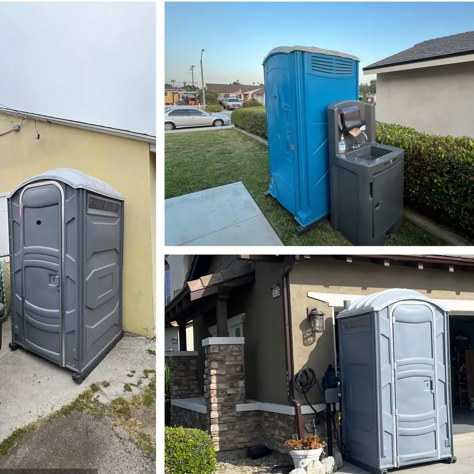 Gray porta potties placed beside homes and a blue unit with a hand-wash station